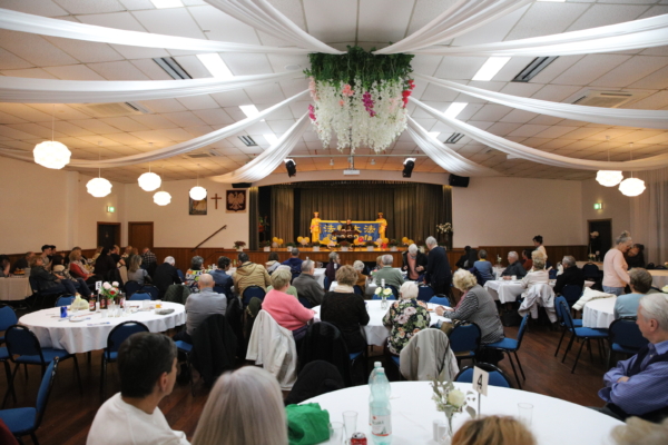 Community members seated at round tables filling the Polish House Syrena hall for the Sunday gathering