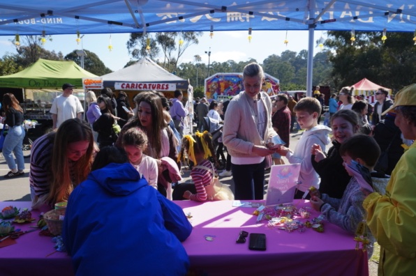 Child making a paper lotus flower at the Falun Dafa booth