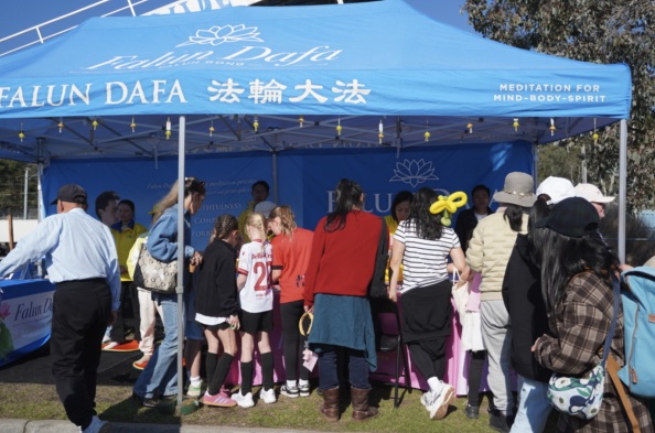 Visitors stopping to watch at the Falun Dafa booth